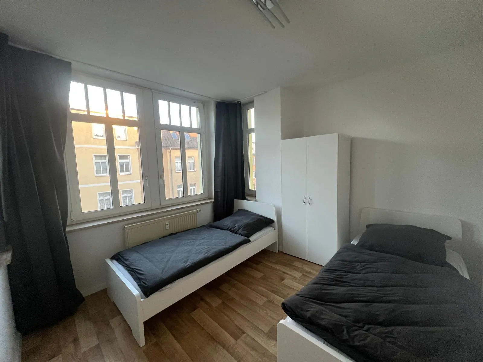 Schlafzimmer mit zwei Betten und großen Fenstern